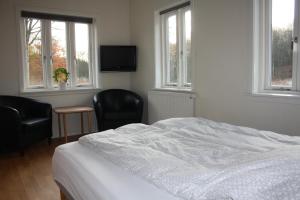 a bedroom with a bed and two chairs and windows at Klærke Hostel in Skanderborg