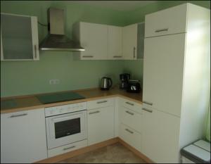 a kitchen with white cabinets and a stove top oven at Ferienwohnung Kohrener Land in Kohren-Sahlis