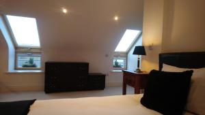 a bedroom with three windows and a bed and a dresser at 10 The Kiln in Westport