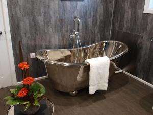 a metal tub in a bathroom with flowers on a table at Beechwood Hotel in North Walsham +28 photos