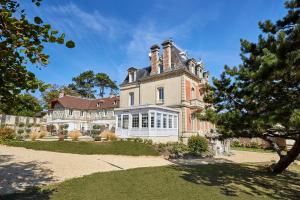 una casa grande con una torreta encima en Les Villas d'Arromanches, Teritoria en Arromanches-les-Bains