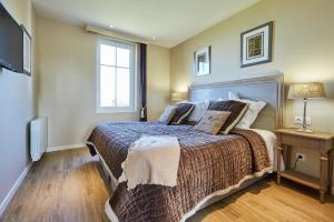 a bedroom with a large bed and a television at Les Villas d'Arromanches, Teritoria in Arromanches-les-Bains