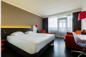 a hotel room with a large white bed and chairs at Postillion Utrecht Bunnik in Bunnik