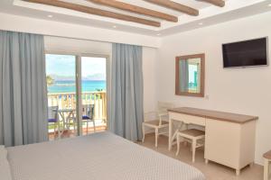 a bedroom with a bed and a desk and a balcony at Mastichari Bay Hotel in Mastihari