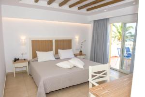 a white bedroom with a bed and a balcony at Mastichari Bay Hotel in Mastihari
