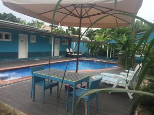 a table and chairs with an umbrella next to a swimming pool at Hotel Avenida in São Tomé