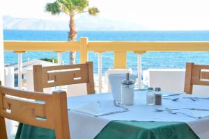 a table with a green and white table cloth and the ocean at Mastichari Bay Hotel in Mastihari