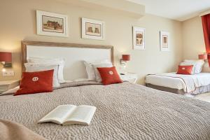 a bedroom with two beds with a book on it at Les Villas d'Arromanches, Teritoria in Arromanches-les-Bains