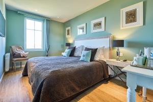 a bedroom with a large bed with blue walls at Les Villas d'Arromanches, Teritoria in Arromanches-les-Bains