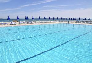 a large swimming pool next to a beach with umbrellas at Mastichari Bay Hotel in Mastihari