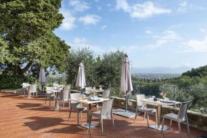 Villa Zelma في Cantagrillo: فناء به طاولات وكراسي ومظلات