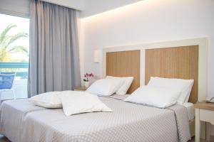 a bedroom with two beds with white sheets and a window at Mastichari Bay Hotel in Mastihari