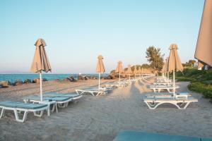 a row of lounge chairs and umbrellas on a beach at Mastichari Bay Hotel in Mastihari