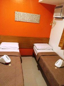 two beds in a room with an orange wall at Stone House Hotel Pasay in Manila
