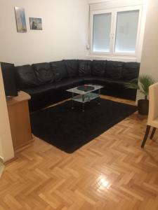 a black leather couch in a living room with a table at Apartman PEŠAČKA ZONA in Šabac