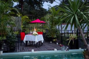 a table with a candle and red chairs next to a pool at De Sarann Villa in Siem Reap