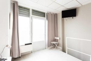 Zimmer mit einem Fenster, einem Stuhl und einem TV in der Unterkunft Small Is Beautiful Ideally Located Sleeps 4 in Paris