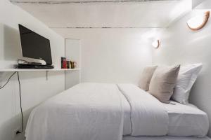 ein weißes Schlafzimmer mit einem Bett und einem TV auf einem Regal in der Unterkunft Small Is Beautiful Ideally Located Sleeps 4 in Paris