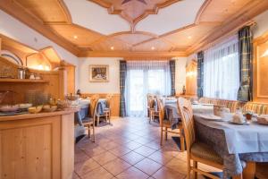 una sala da pranzo con tavoli, sedie e soffitto di Garni Edera a Corvara in Badia