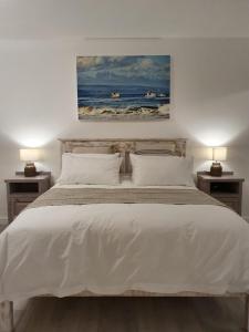 Un dormitorio con una cama blanca con dos mesitas de noche. en Valley View, en Plettenberg Bay