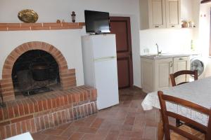 a kitchen with a brick fireplace with a white refrigerator at La Casina di Nonna Lola in Castiglione dʼOrcia