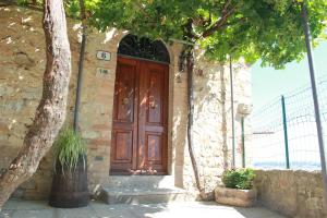a wooden door on a stone building with a tree at La Casina di Nonna Lola in Castiglione dʼOrcia