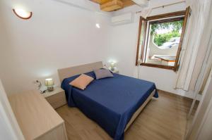 una camera con un letto blu e una finestra di A.I.R. Villa Marinedda a Isola Rossa