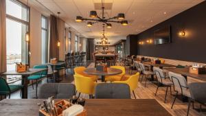 un restaurant avec des tables, des chaises et des fenêtres dans l'établissement the niu Fender, à Amsterdam