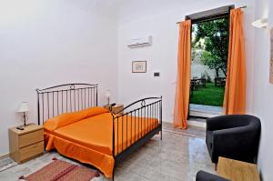 a bedroom with a bed and a chair and a window at Il Giardino Del Barocco in Noto