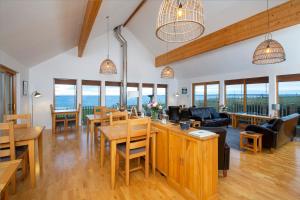 a living room with tables and chairs and windows at Broad Bay House in Stornoway