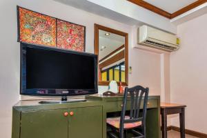 a television on a green desk with a chair at OYO 447 Royal Express Hua Hin in Hua Hin