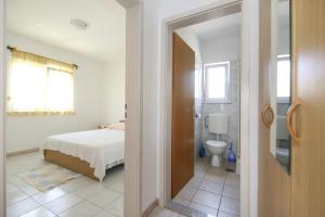 a white bedroom with a bed and a toilet at Apartments Tea - parking and grill, 100 m from sea in Rogoznica