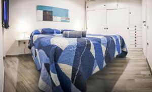 a bedroom with a bed with a blue and white quilt at Pinus Village Apartments in Santa Margherita di Pula