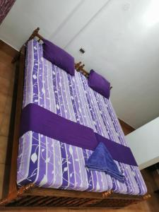 Una cama con sábanas y almohadas moradas. en Stay Well Ayurvedic Beach Resort, en Kovalam