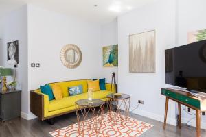 - un salon avec un canapé jaune et une télévision dans l'établissement 24 Molyneux Street, à Londres
