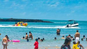a group of people on a beach with a boat at Le Soleil Pousada e Restaurante in Praia do Frances