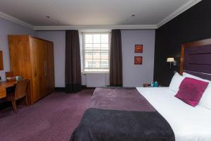a hotel room with a large bed and a desk at Fletcher's Restaurant Bar & Rooms in Stirling