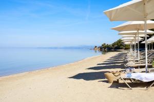 una fila de sillas y sombrillas en una playa en Anthemus Sea Beach Hotel and Spa en Elia