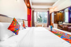 1 dormitorio con 1 cama grande y almohadas coloridas en FabHotel Marble Arch en Nueva Delhi
