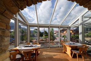 a large conservatory with tables and chairs and windows at Hotel garni Alpengruss in Garmisch-Partenkirchen