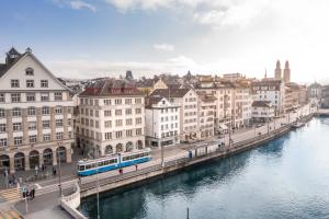 a city with a river and buildings and a train at Pop Up Hotel Krone Zürich in Zurich