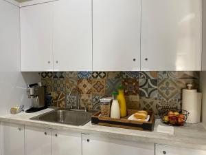 a kitchen counter with a sink and white cabinets at Fortel Hostel in San Juan