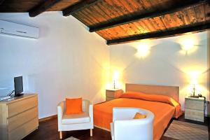 a bedroom with a bed and a tv and a chair at Il Giardino Del Barocco in Noto