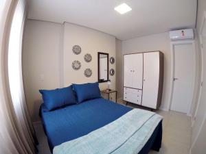 a bedroom with a blue bed and a white cabinet at Suíte Moderna Master Collection in Passo Fundo