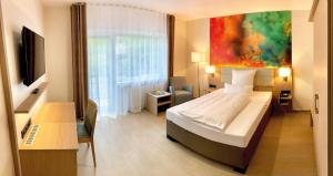 ein Schlafzimmer mit einem Bett, einem Schreibtisch und einem Fernseher in der Unterkunft Thermalhotel Kemper in Erwitte
