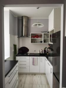 una cocina con armarios blancos y electrodomésticos negros en Apartament Detka, en Nowy Targ