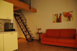 sala de estar con sofá rojo y escalera de caracol en Caterina Residence, en Faenza