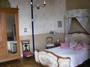 - une chambre avec un lit à baldaquin et des oreillers roses dans l'établissement La Mailholière, à Blanzay