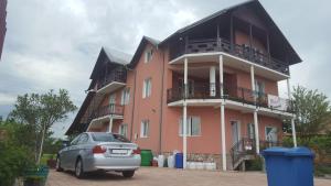 a car parked in front of a pink building at Casa Reds in Râmnicu Vâlcea