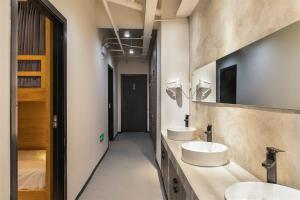 twee wastafels in een badkamer met twee spiegels bij Wander Hostel in Haikou